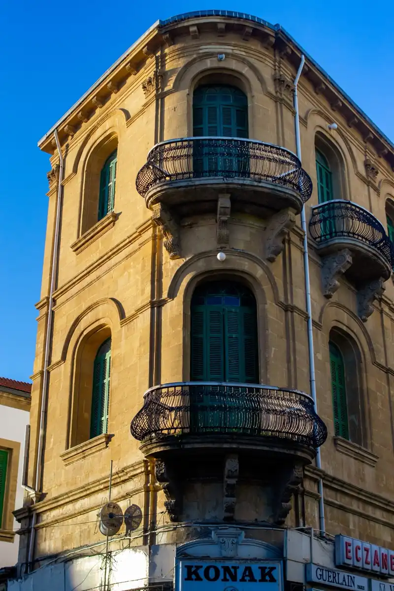 Historic stone building with curved balconies and green shutters